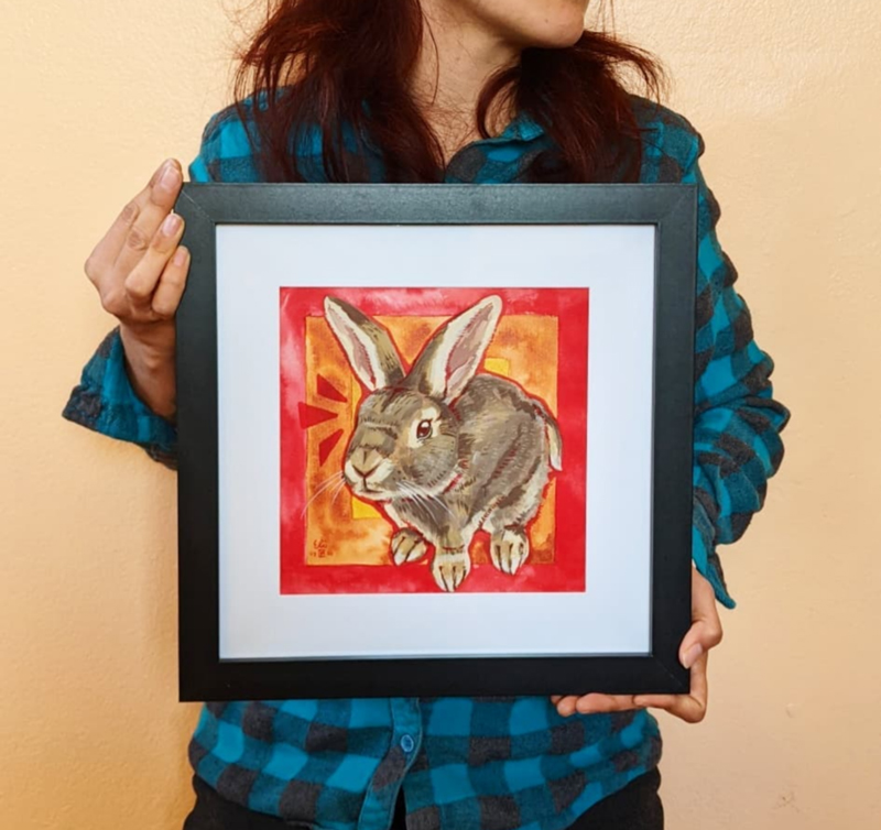 Artist holding a framed portrait of a bunny