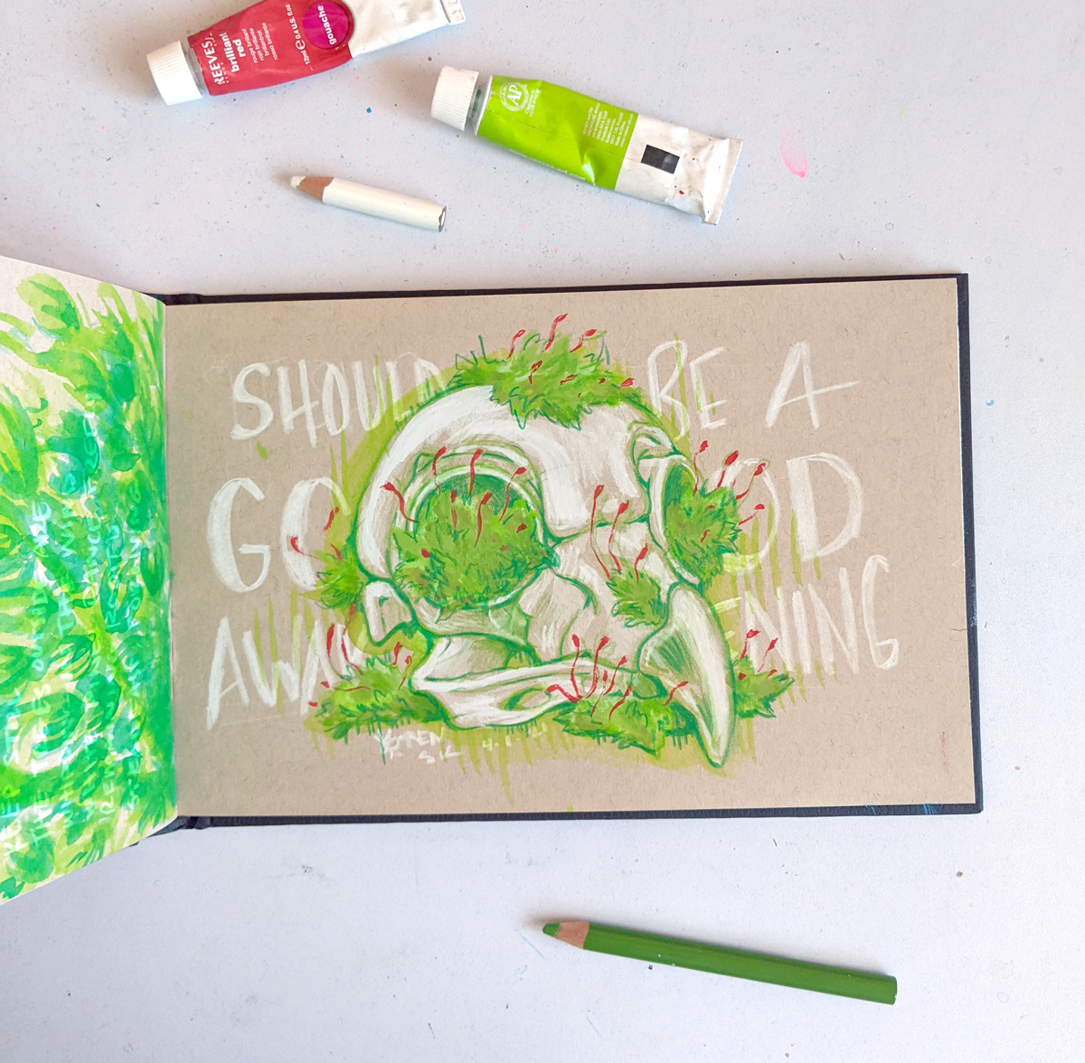 Sketchbook open to a drawing of a bird skull with moss growing on it, text behind says "SHOULD BE A GOOD AWAKENING"