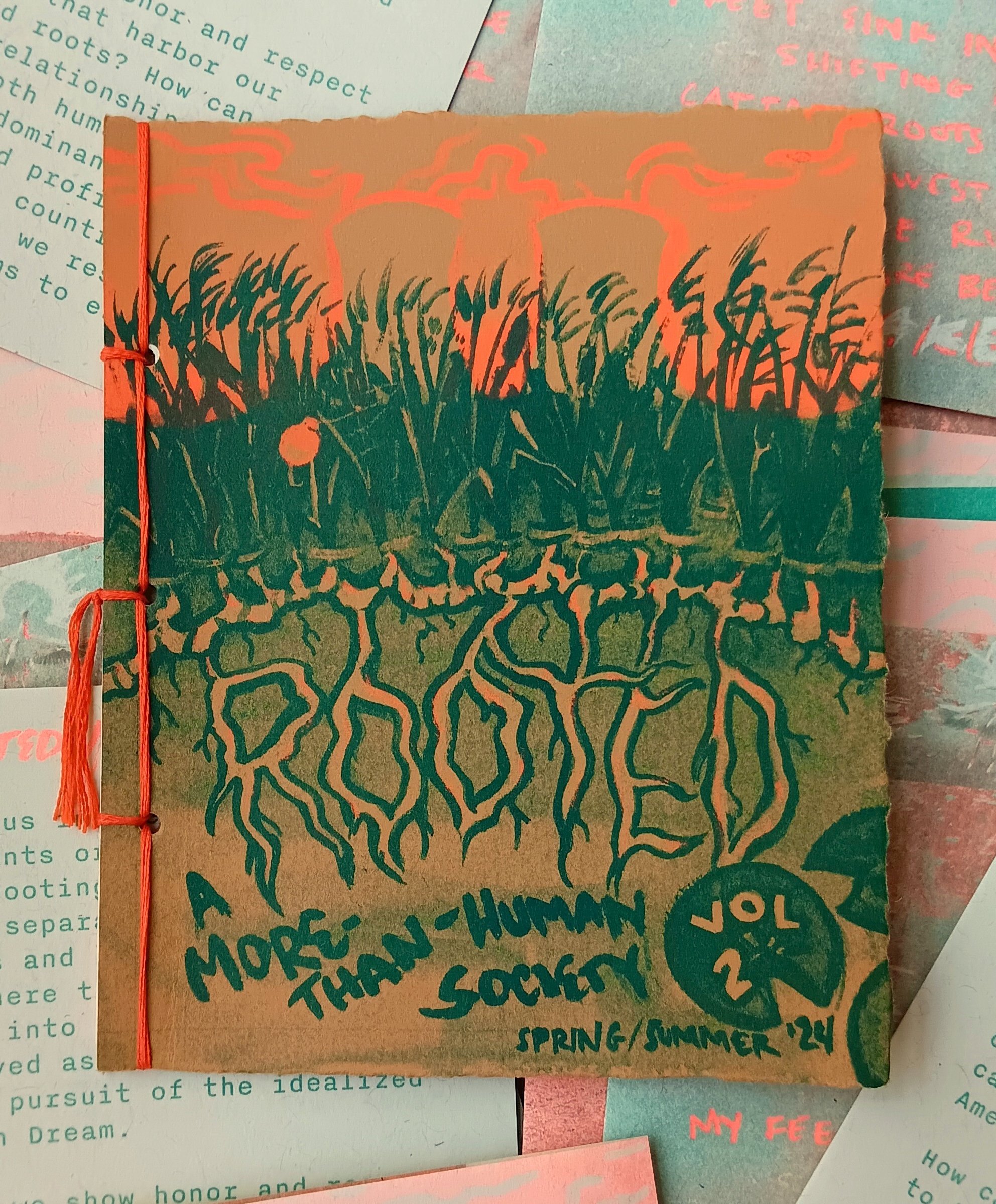 Zine in neon orange and green on inner pages. Features wetlands with nuclear power plant looming behind. ROOTED is the issue