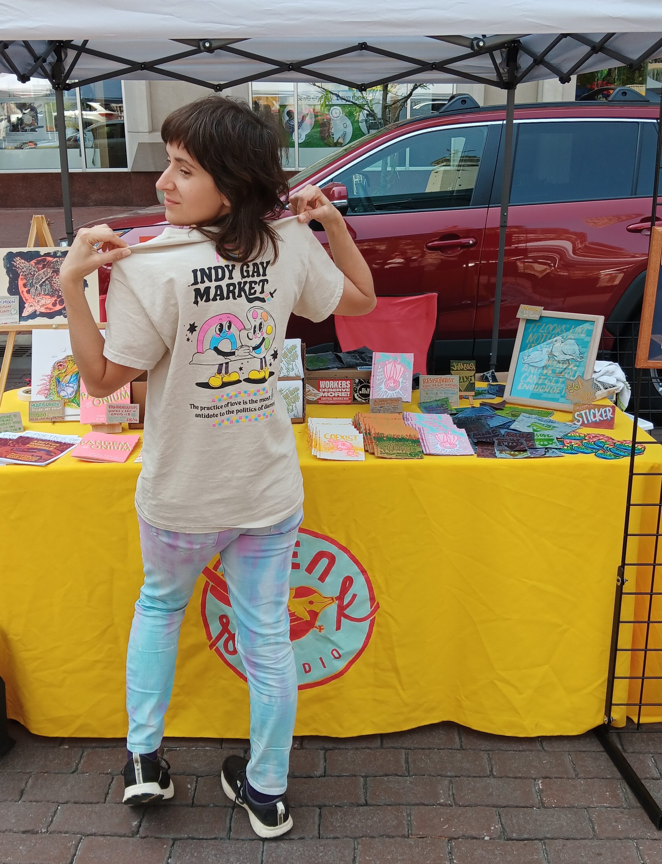 Me, the artist in front of my yellow booth showing off my indy gay market tshirt